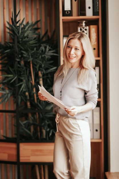 Una mujer de negocios sonriente parada en la oficina presentando su trabajo a los colegas