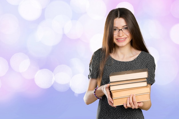 Mujer de negocios sonriente que sostiene la pila de libros