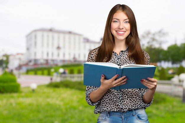 Mujer de negocios sonriente que sostiene la pila de libros