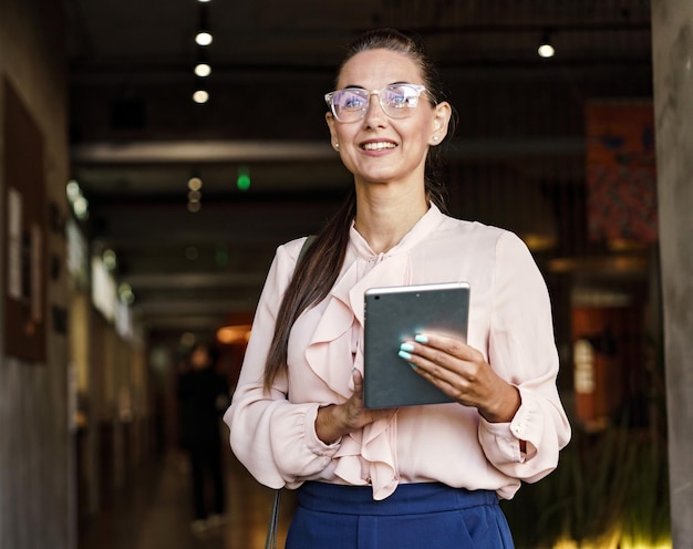 Foto una mujer de negocios sonriente con una tableta en un vibrante pasillo corporativo que encarna el éxito y la positividad