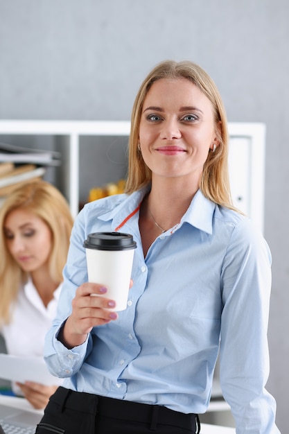 Mujer de negocios sonriente tomando café de un vaso de papel