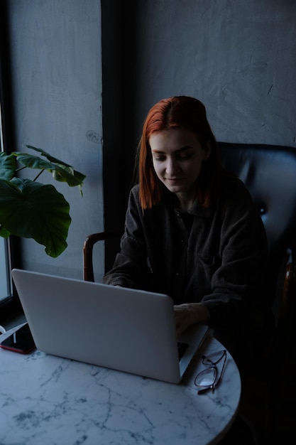 Una mujer de negocios sonriente usando una computadora portátil en un café