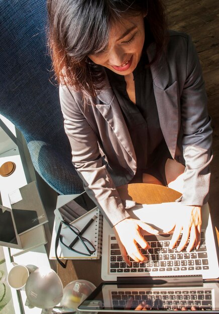 Foto mujer de negocios sonriente usando una computadora portátil mientras está sentada en la mesa en la oficina