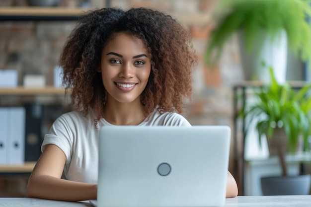 Una mujer de negocios sonriente usando una computadora portátil en su oficina en casa