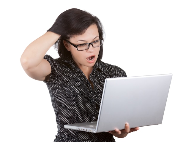 Mujer de negocios sorprendida en gafas trabajando en la computadora portátil sobre un fondo blanco.