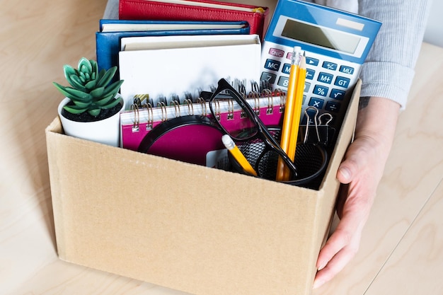 Mujer de negocios sosteniendo una caja de cartón con pertenencias personales de la empresa