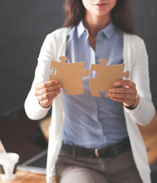 Mujer de negocios sosteniendo y señalando una pieza del rompecabezas