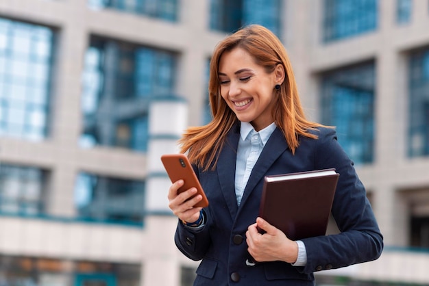 Mujer de negocios sosteniendo su teléfono para enviar un mensaje