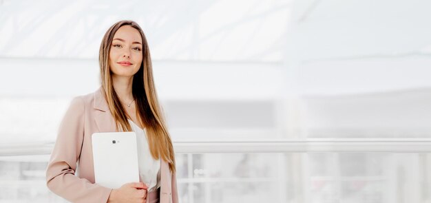 Mujer de negocios sosteniendo tableta digital de pie en el centro de negocios