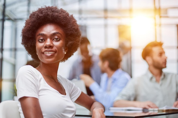 Mujer de negocios con su personal al fondo en la oficina