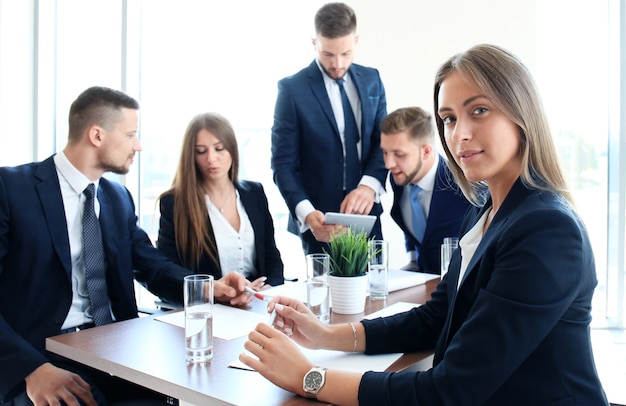 Mujer de negocios con su personal, grupo de personas en segundo plano en la oficina moderna y luminosa en el interior