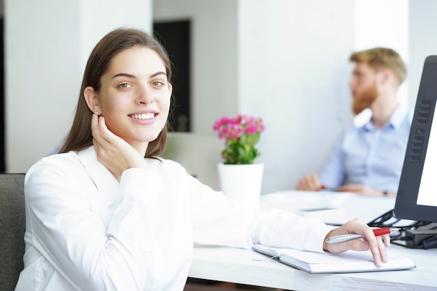 Mujer de negocios con su personal, grupo de personas en segundo plano en la oficina moderna y luminosa en el interior