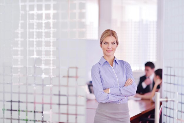 Foto mujer de negocios con su personal, grupo de personas en segundo plano en una oficina moderna y luminosa en el interior