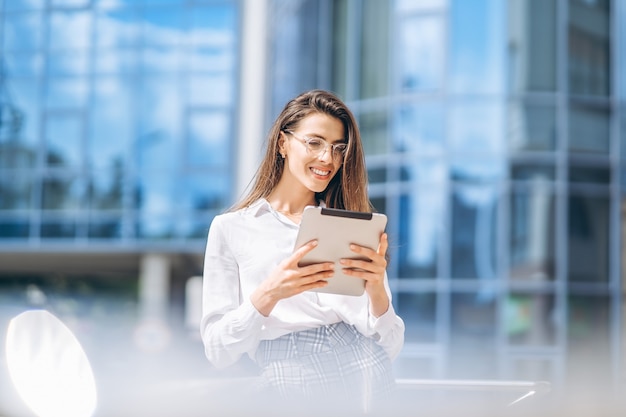 Mujer de negocios con tableta cerca del moderno centro de negocios.