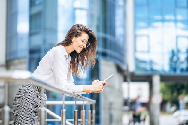 Mujer de negocios con tableta cerca del moderno centro de negocios.