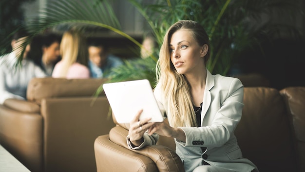 Mujer de negocios con una tableta digital sentada en el sofá