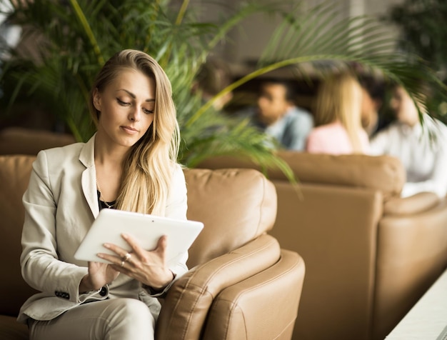 Mujer de negocios con una tableta digital sentada en el sofá