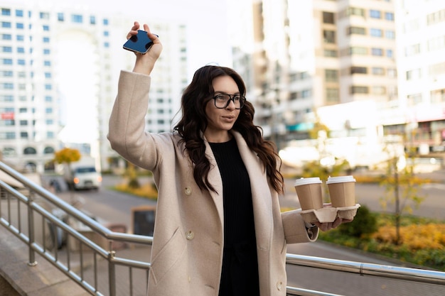 Mujer de negocios con una taza de café en las manos saludando a su colega cerca de la oficina