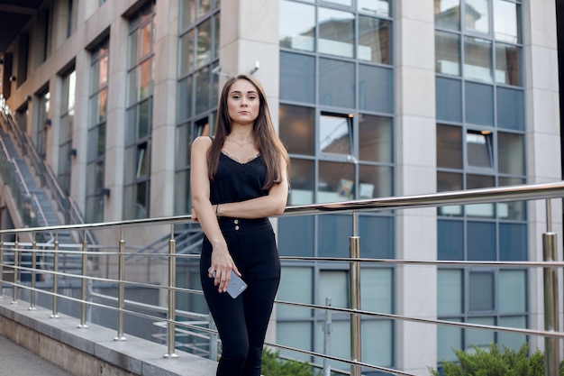 Mujer de negocios con teléfono cerca de la oficina. Retrato de hermosa mujer sonriente en ropa de oficina de moda hablando por teléfono mientras está de pie al aire libre. Comunicación telefónica. Imagen de alta calidad.