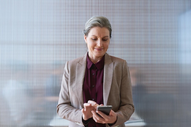 Mujer de negocios por teléfono y escribiendo en las redes sociales de la oficina o navegando por Internet en línea Teléfono celular de tecnología y directora ejecutiva senior feliz con teléfono inteligente móvil para enviar mensajes de texto en red o desplazarse por la web