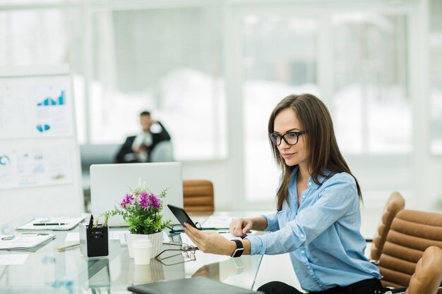 Mujer de negocios con un teléfono inteligente en el lugar de trabajo en una oficina moderna.