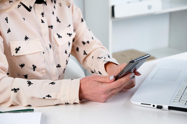 Mujer de negocios tiene un teléfono inteligente móvil en las manos y se comunica en línea a través de Internet en su lugar de trabajo Trabajo en línea independiente concepto de negocio y tecnología de conexión mundial