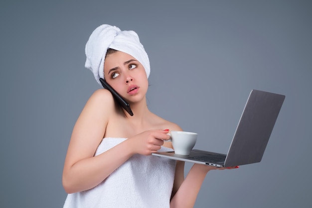 Mujer de negocios con una toalla en la cabeza con una taza de café trabajando en una laptop hablando por teléfono retrato de wom