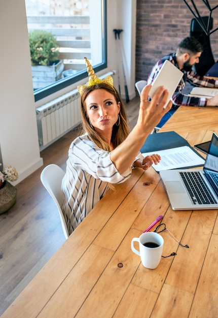 Mujer de negocios tomando selfie con diadema de unicornio