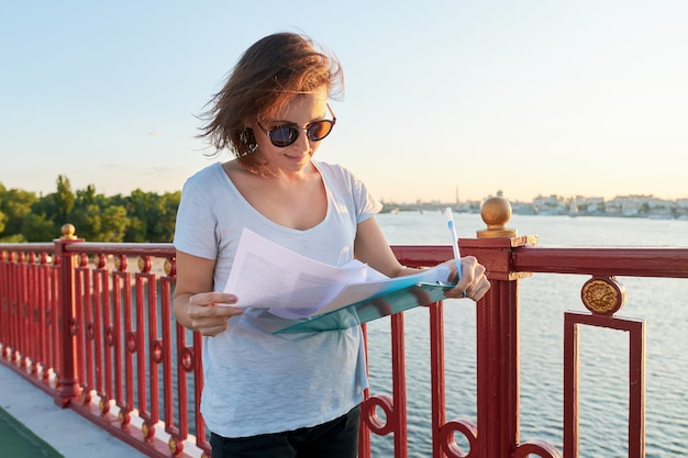 Mujer de negocios trabajando al aire libre, mujer con documento en papel en el portapapeles, trabajador social entrevistando a personas en la calle