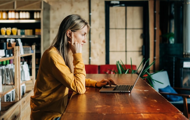Mujer de negocios trabajando en una computadora portátil mientras está sentada en una mesa en una cafetería