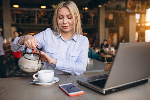 Mujer de negocios trabajando en la computadora portátil y el teléfono en un café