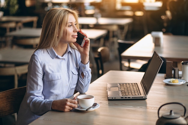 Mujer de negocios trabajando en la computadora portátil y el teléfono en un café