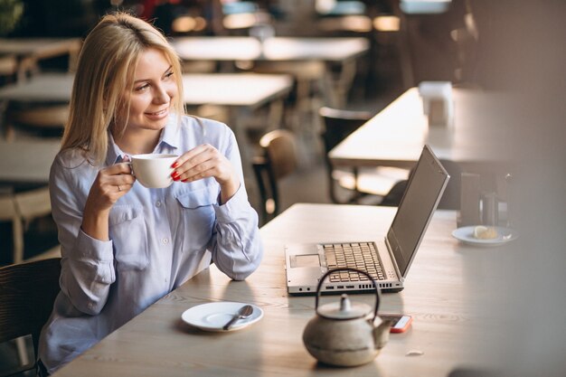 Mujer de negocios trabajando en la computadora portátil y el teléfono en un café