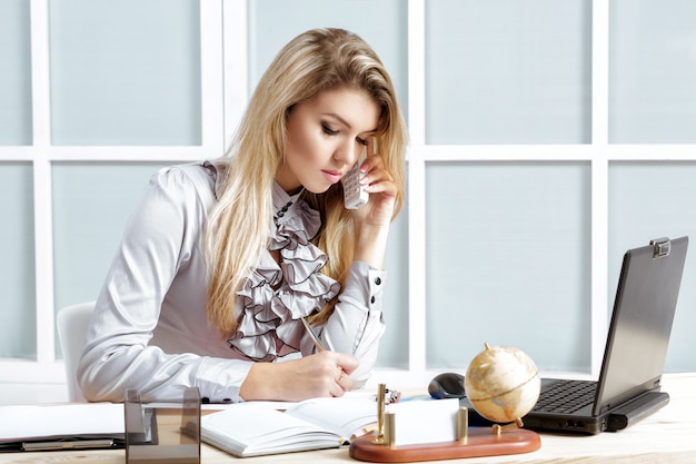 Mujer de negocios trabajando en el escritorio y hablando por teléfono