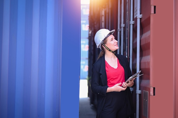 Mujer de negocios Trabajar en un área de patio de envío internacional Servicio de entrega de exportación e importación con contenedores