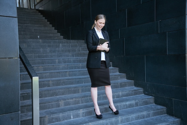 Mujer de negocios en un traje con un diario se encuentra en los pasos