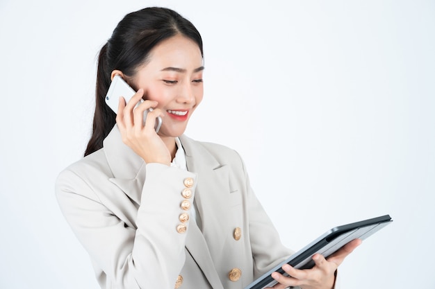 Mujer de negocios en traje gris con teléfono y tableta para conectarse con los clientes.