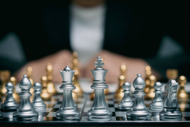 Mujer de negocios con un traje juega al ajedrez. Primer plano de una mano femenina en un concepto de negocio de competencia de juego de tablero de ajedrez de peón, enfoque selectivo en piezas de ajedrez, concepto de negocio de ajedrez, líder y éxito.