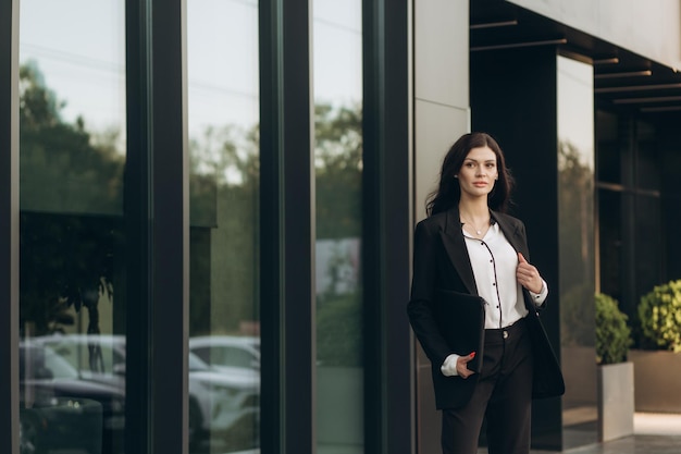mujer de negocios en un traje de pie cerca de un edificio de oficinas