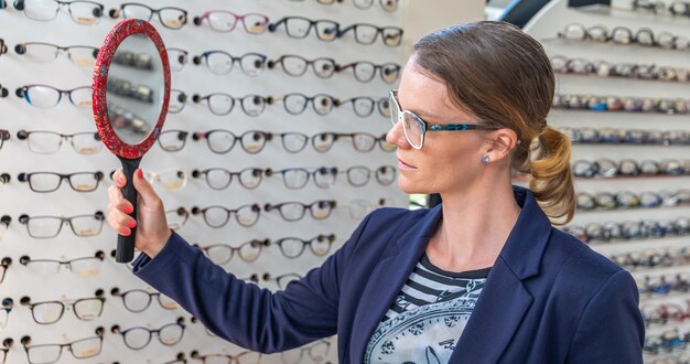 Mujer de negocios trata de gafas delante de un espejo en una tienda de óptica