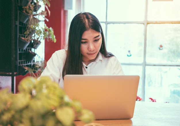 Mujer de negocios usando una computadora portátil en la mesa de una cafetería