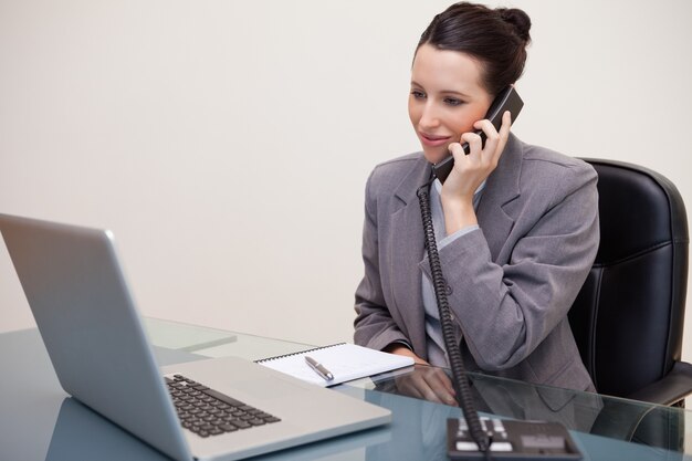 Mujer de negocios usando la computadora portátil mientras está en llamada