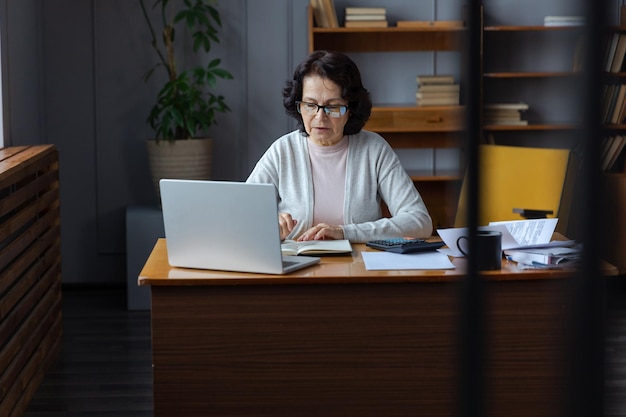 Foto mujer de negocios usando una computadora portátil mientras está sentada en la mesa