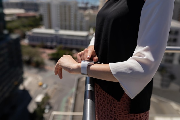 Mujer de negocios usando un reloj inteligente en el balcón de la oficina