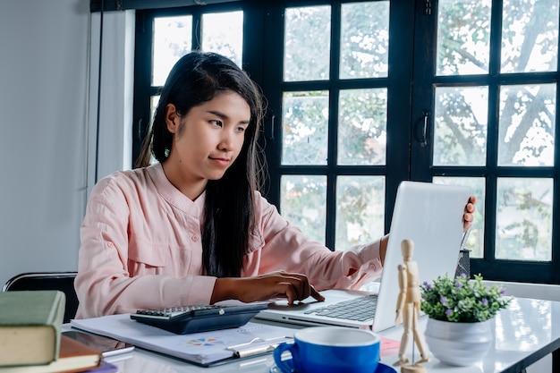 Mujer de negocios usando su computadora portátil y mirando la pantalla del ordenador portátil mientras se planea el concepto de pensamiento