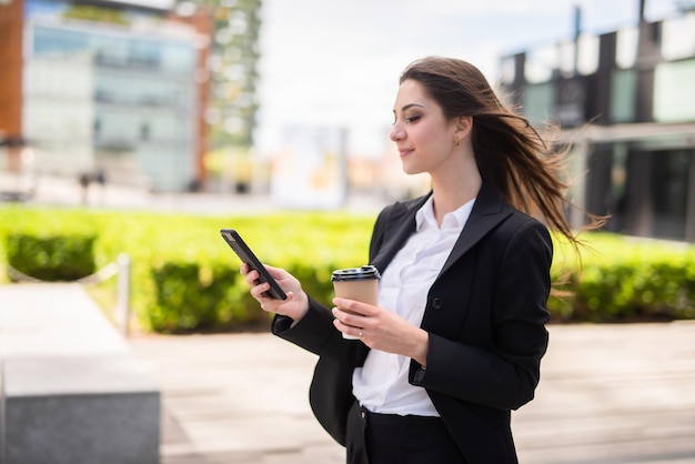 Mujer de negocios usando su teléfono móvil mientras camina al aire libre