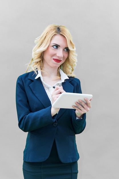Mujer de negocios usando una tableta digital mientras está de pie contra un fondo gris