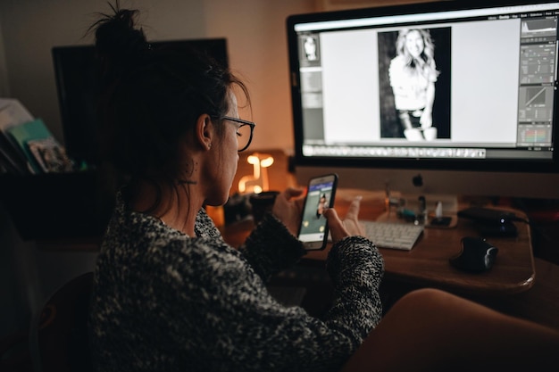 Mujer de negocios usando teléfono y computadora en casa
