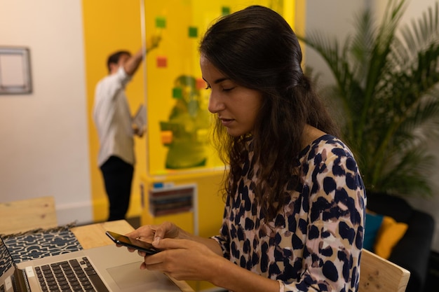 Mujer de negocios usando teléfono móvil en una mesa en una oficina moderna