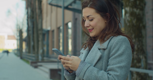 Mujer de negocios utiliza smartphone cerca del centro de negocios.